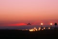 Plane lands at an airfield on the background of red clouds Royalty Free Stock Photo