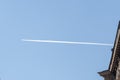 The plane leaves an inversion trail against the blue sky and the roof of an old European building, a place for your text, copy spa Royalty Free Stock Photo