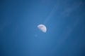 plane passing through the Moon from bottom view with long condensation tail on blue sky Royalty Free Stock Photo