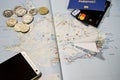 The plane, smartphone, biometric passport, dollars, coins and credit cards lie on a map
