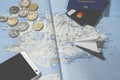 The plane, smartphone, biometric passport, dollars, coins and credit cards lie on a map