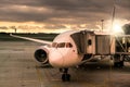 The plane stands with a tunnel at the airport at sunset Royalty Free Stock Photo