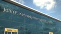 Taking off airplane reflecting in the modern windows with John F. Kennedy International Airport text, 3d rendering