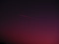 The plane and the trail in the crimson-burgundy sky. Abstract background on space or aero theme Royalty Free Stock Photo