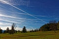 Many plane trails in blue sky over late fall landscape