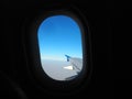 The plane window. The porthole through which you can see the plane's wing, blue sky, misty horizon and earth in a haze Royalty Free Stock Photo