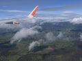 Plane wing with the blue sky and mainland covered with clouds