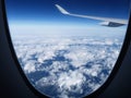 Plane wing with the blue sky and mainland covered with clouds