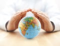 Planet Earth globe protected by hands.