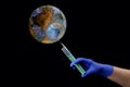 Planet earth infected with a virus, a hand in a medical glove with a syringe makes an injection, covid-19, the virus black