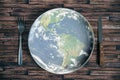 The planet Earth plate with a fork and knife on a wooden background. World hunger concept. Feed the world Royalty Free Stock Photo