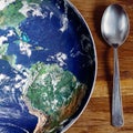 The planet Earth plate with a fork and knife on a wooden background. World hunger concept. Feed the world Royalty Free Stock Photo