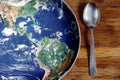 The planet Earth plate with a fork and knife on a wooden background. World hunger concept. Feed the world Royalty Free Stock Photo