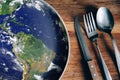 The planet Earth plate with a fork and knife on a wooden background. World hunger concept. Feed the world Royalty Free Stock Photo