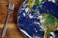 The planet Earth plate with a fork and knife on a wooden background. World hunger concept. Feed the world Royalty Free Stock Photo