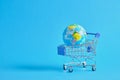 a planet earth in a supermarket shopping cart on blue background. copy space Royalty Free Stock Photo