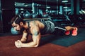 Muscled young man wearing sport wear and doing plank position while exercising on the floor in loft interior Royalty Free Stock Photo