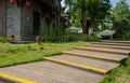 Plank-paved stairway in lawn before traditional buildings on sun