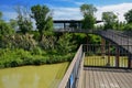 Plank-paved steel footbridge over river in sunny summer afternoon