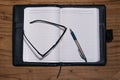 Daily planner book in black leather case with glasses and pen Royalty Free Stock Photo