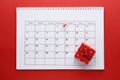 Planning calendar with pin 1th new year. On a red background with a red gift box. Important date. Place for text.