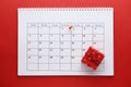 Planning calendar with pin 1th new year. On a red background with a red gift box. Important date.