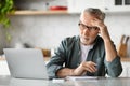 Planning Concept. Pensive Senior Man Using Laptop And Writing In Notebook Royalty Free Stock Photo