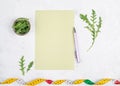 Planning a diet, arugula salad and tailor tape measure around the empty paper, healthy food and lifestyle, loosing weight Royalty Free Stock Photo