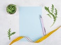 Planning a diet, arugula salad and tailor tape measure around the empty paper, healthy food and lifestyle, loosing weight Royalty Free Stock Photo