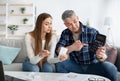 Planning family budget. Mature couple with calculator decicing on bill payments, planning expenses at home Royalty Free Stock Photo