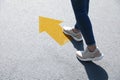 Planning future. Woman walking to drawn mark on road, closeup. Yellow arrow showing direction of way Royalty Free Stock Photo