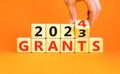 Planning 2024 grants new year symbol. Businessman turns a wooden cube and changes words Grants 2023 to Grants 2024. Beautiful