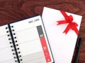 calendar diary planner with date of December and January in grid and envelope with red ribbon bow and pen on wooden desk floor Royalty Free Stock Photo