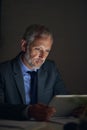 Planning late into the night. a mature businessman using a digital tablet while working late in an office. Royalty Free Stock Photo