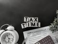 Tax-filling concept - Tax time words on wooden blocks with the U.S IRS 1040 form,pen,calculator and clock in vintage background