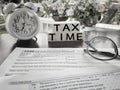 Tax-filling concept - Tax time words on wooden blocks with the U.S IRS 1040 form,eyeglasses and clock in vintage background