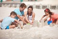 Planning the most magnificent castle ever...a happy family building sandcastles together at the beach.