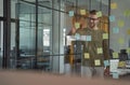 Planning new project. Young caucasian man, office worker wearing glasses writing something on sticky notes on a glass Royalty Free Stock Photo