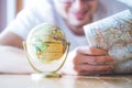 Planning the next journey: Man with map and miniature globe on the floor Royalty Free Stock Photo
