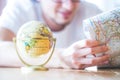 Planning the next journey: Man with map and miniature globe on the floor Royalty Free Stock Photo