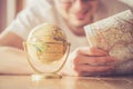Planning the next journey: Man with map and miniature globe on the floor Royalty Free Stock Photo