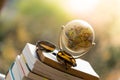 Planning the next journey: Miniature globe and sunglasses on a stack of books