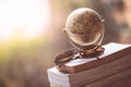 Planning the next journey: Miniature globe and sunglasses on a stack of books