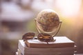 Planning the next journey: Miniature globe and sunglasses on a stack of books