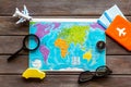 Planning a travel concept. Map of the world and tourist accessories on dark wooden background top view Royalty Free Stock Photo