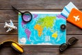 Planning a travel concept. Map of the world and tourist accessories on dark wooden background top view Royalty Free Stock Photo