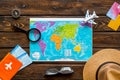 Planning a travel concept. Map of the world and tourist accessories on dark wooden background top view Royalty Free Stock Photo