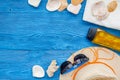 Summer travaling to the sea with straw hat, sun glasses, sunblock lotion on blue wooden background top view mock up