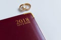 Planning a wedding in 2018. Top view of 2018 personal organizer and two wedding rings on white background with space for text Royalty Free Stock Photo