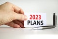 2023 Plans symbol. White paper with words 2023 Plans. Businessman hand. Metallic pen. Beautiful white table white background.